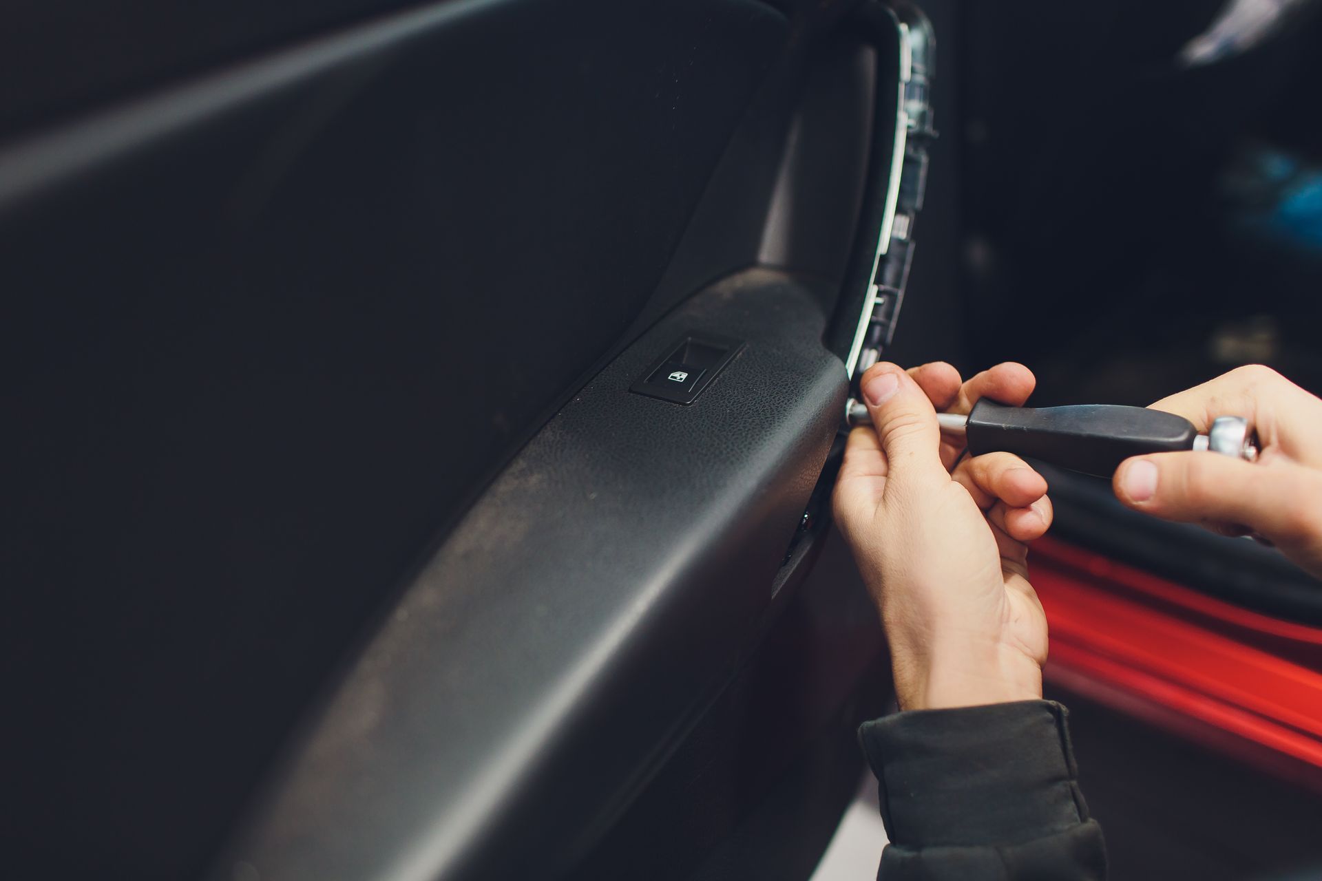 An experienced mechanic meticulously installing a central door lock motor in a car's interior panel.