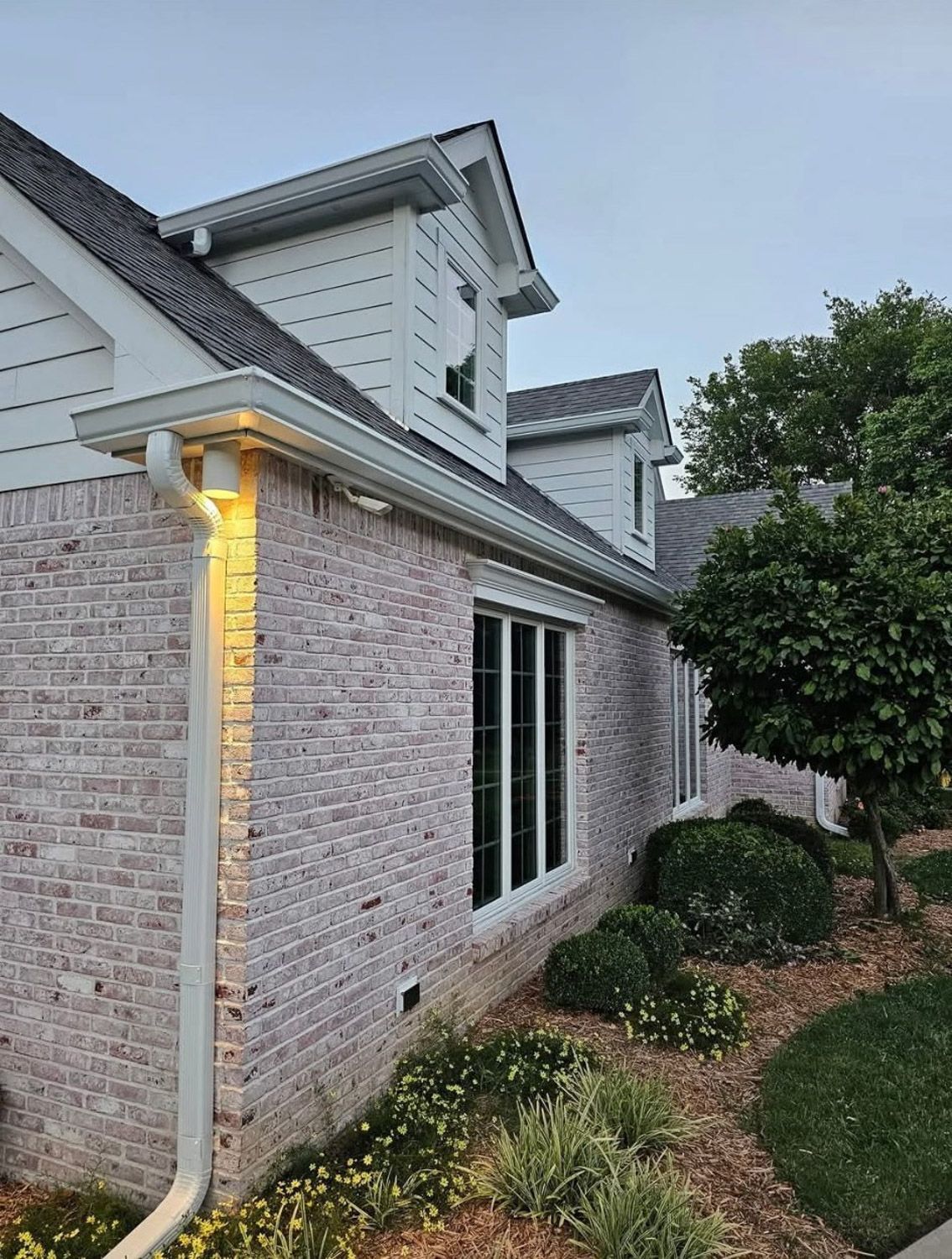 White house with black gutters next to a swimming pool under a blue sky. New seamless gutters installed by Gutter Specialist in Reno, NV