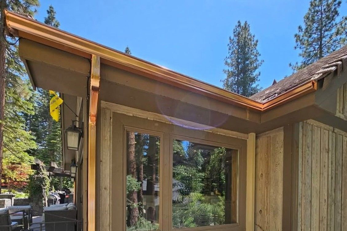Reno home exterior with new copper gutters and window reflecting trees. 