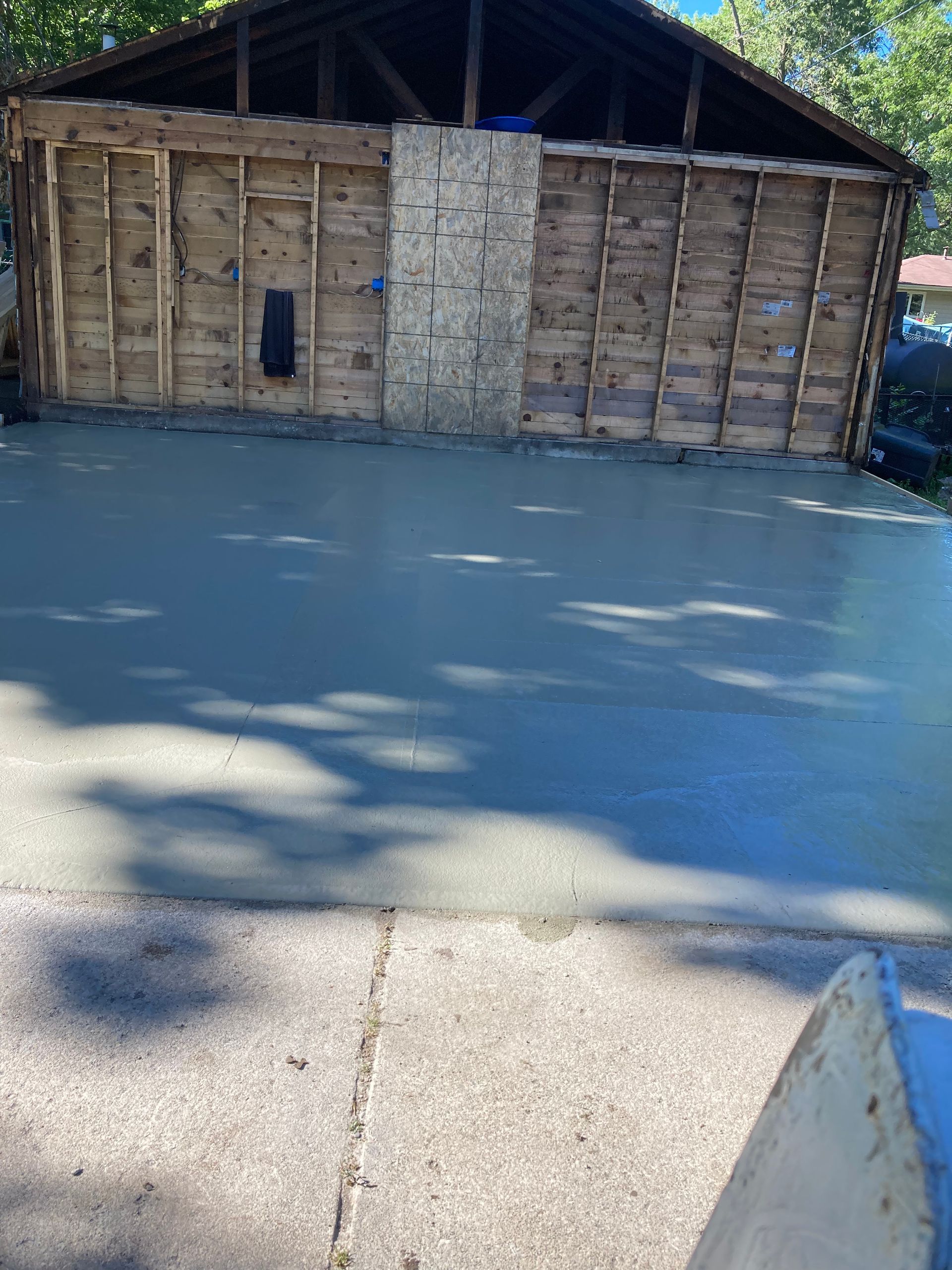 a garage under construction with a concrete driveway in front of it
