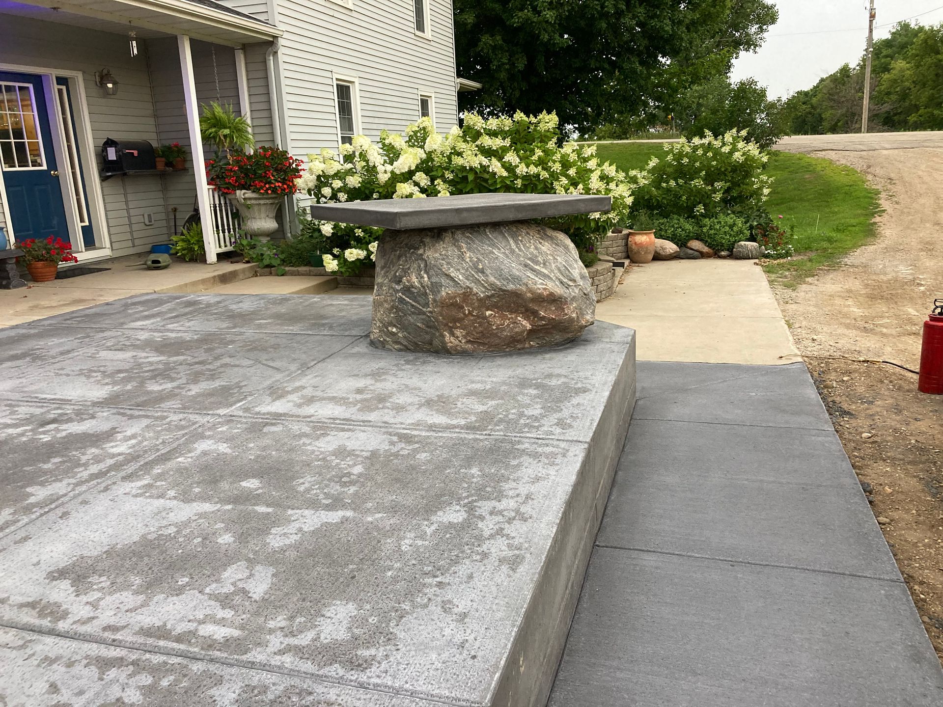 a bench is sitting on top of a rock on a sidewalk in front of a house