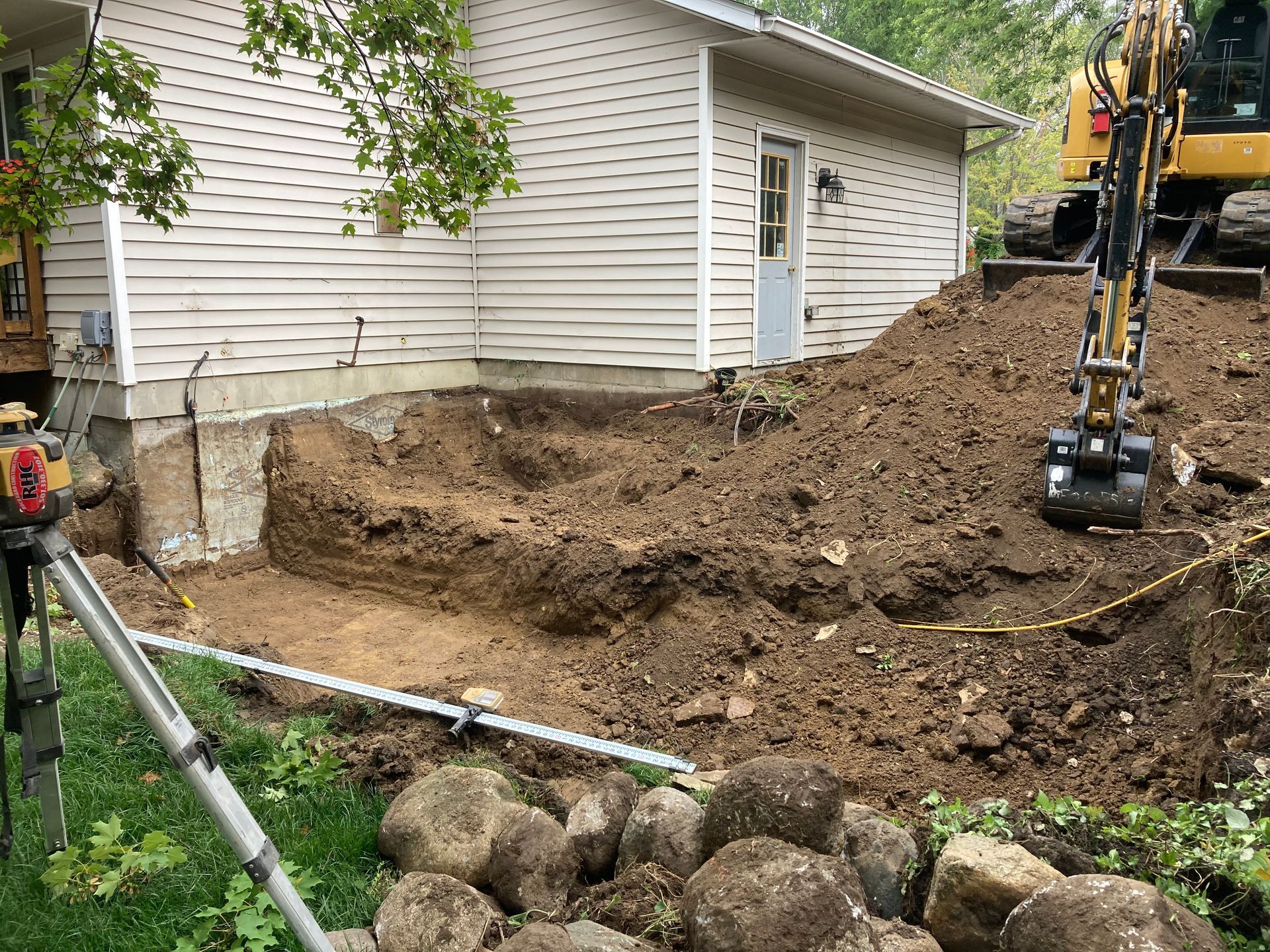 an excavator is digging a hole in front of a house