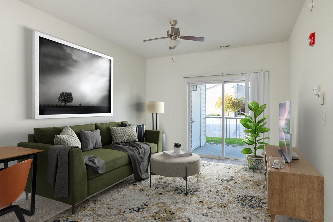 Living room with green sofa, round coffee table, rug, and sliding glass door to balcony.