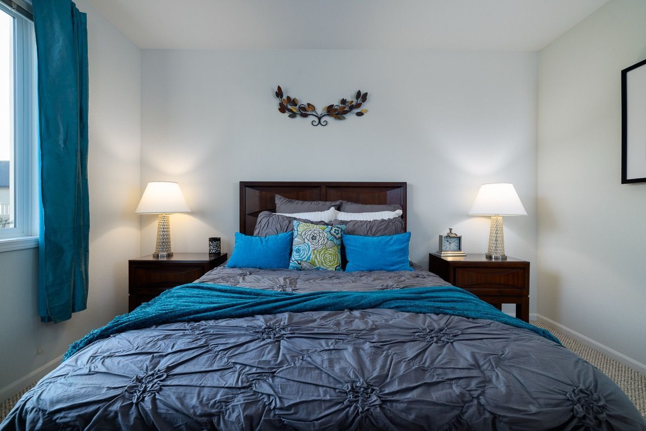 Bedroom with a dark wood bed, two nightstands, lamps, and teal accents.