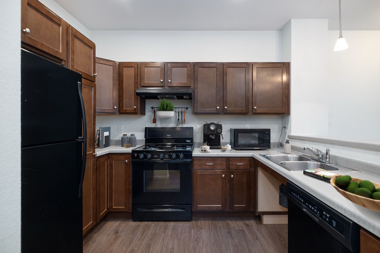 Kitchen with dark wood cabinets, black appliances, and a double sink.
