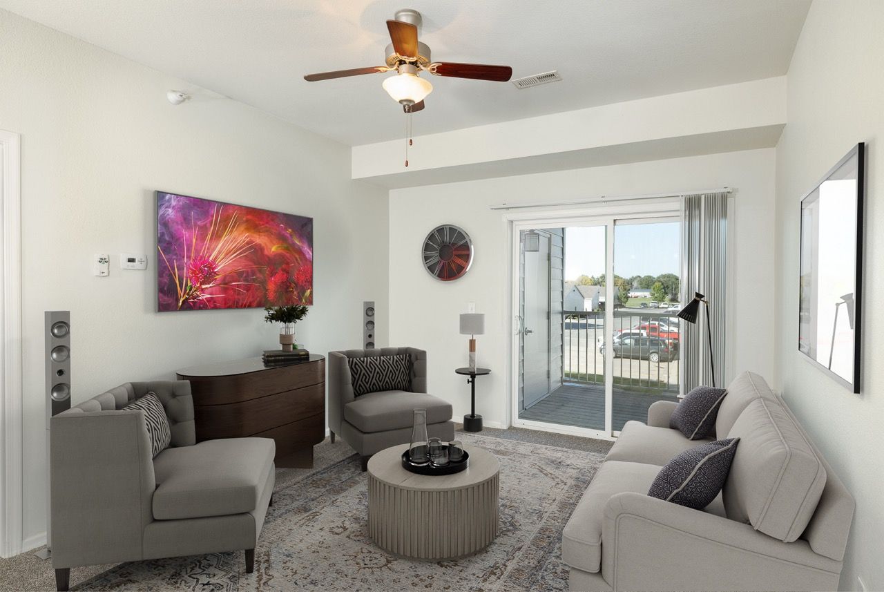 Living room in an apartment with gray seating, a round coffee table, and a sliding glass door to a balcony.
