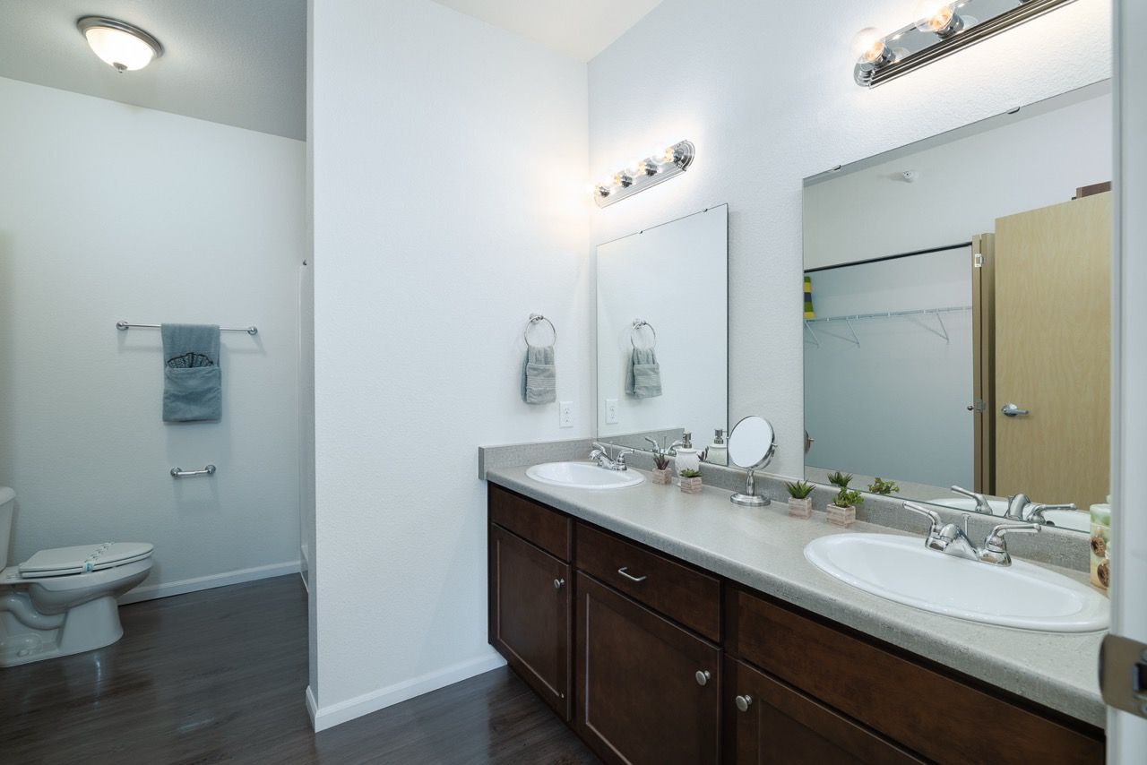 Bathroom with a double-sink vanity, large mirrors, and towels hanging on the wall.