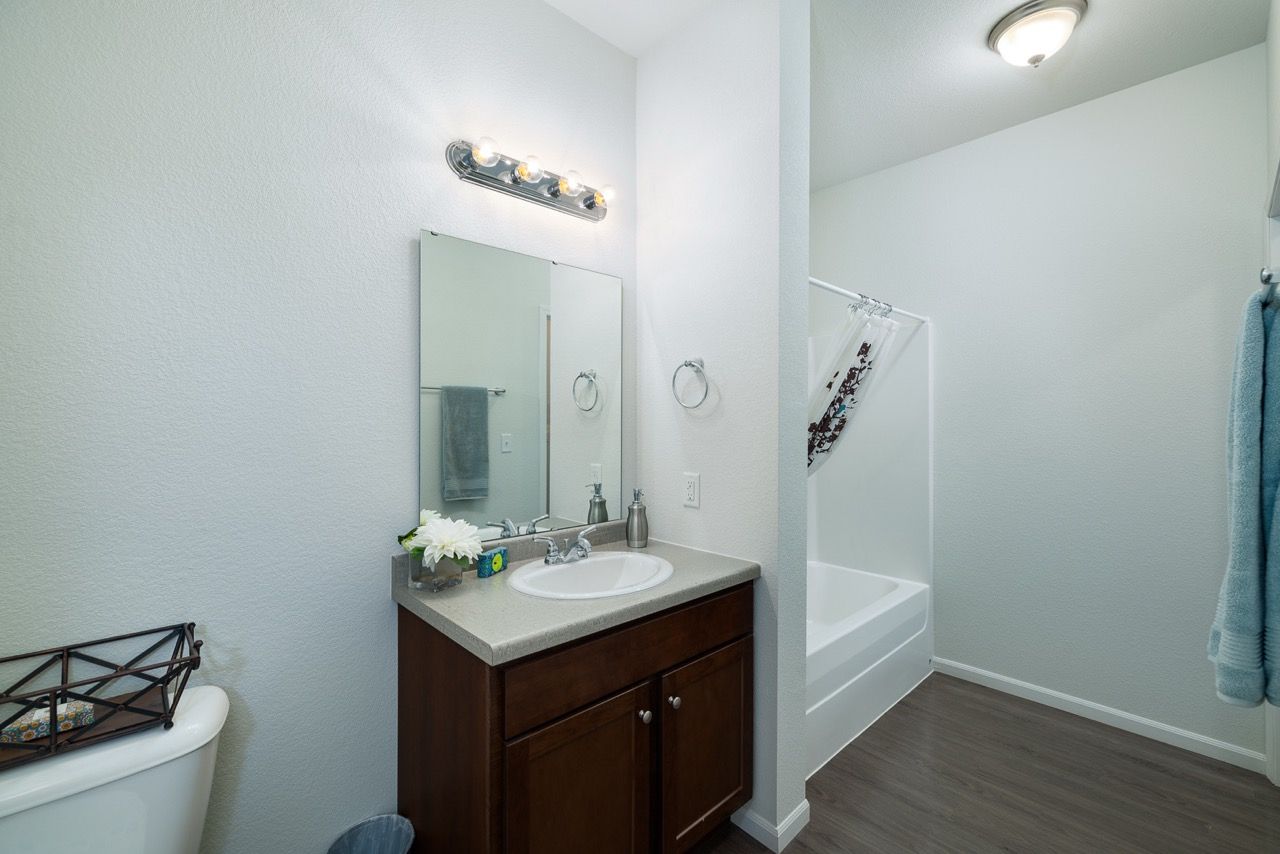 Bathroom in an apartment unit with sink, mirror, vanity, toilet, and bathtub/shower.
