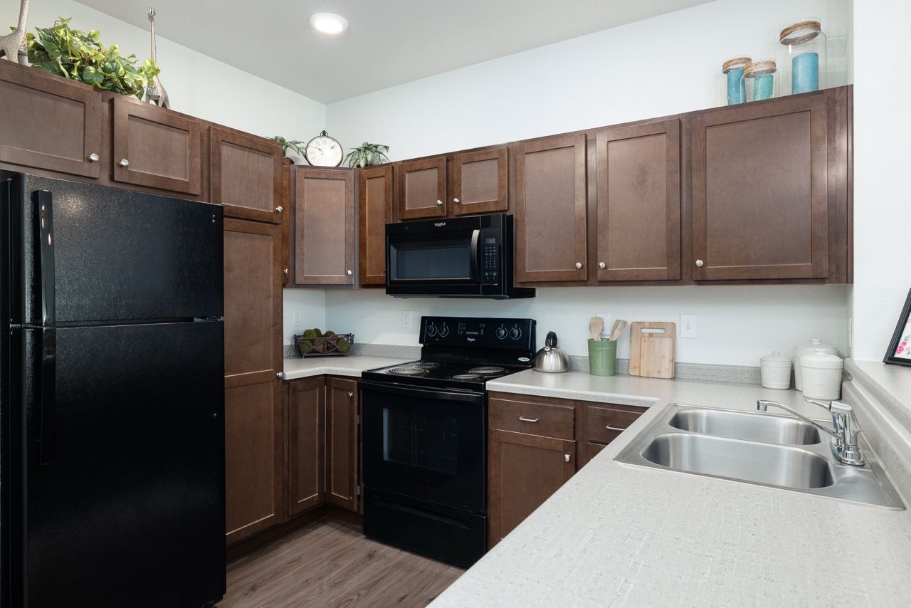 Kitchen with dark wood cabinets, black appliances, and a double sink.