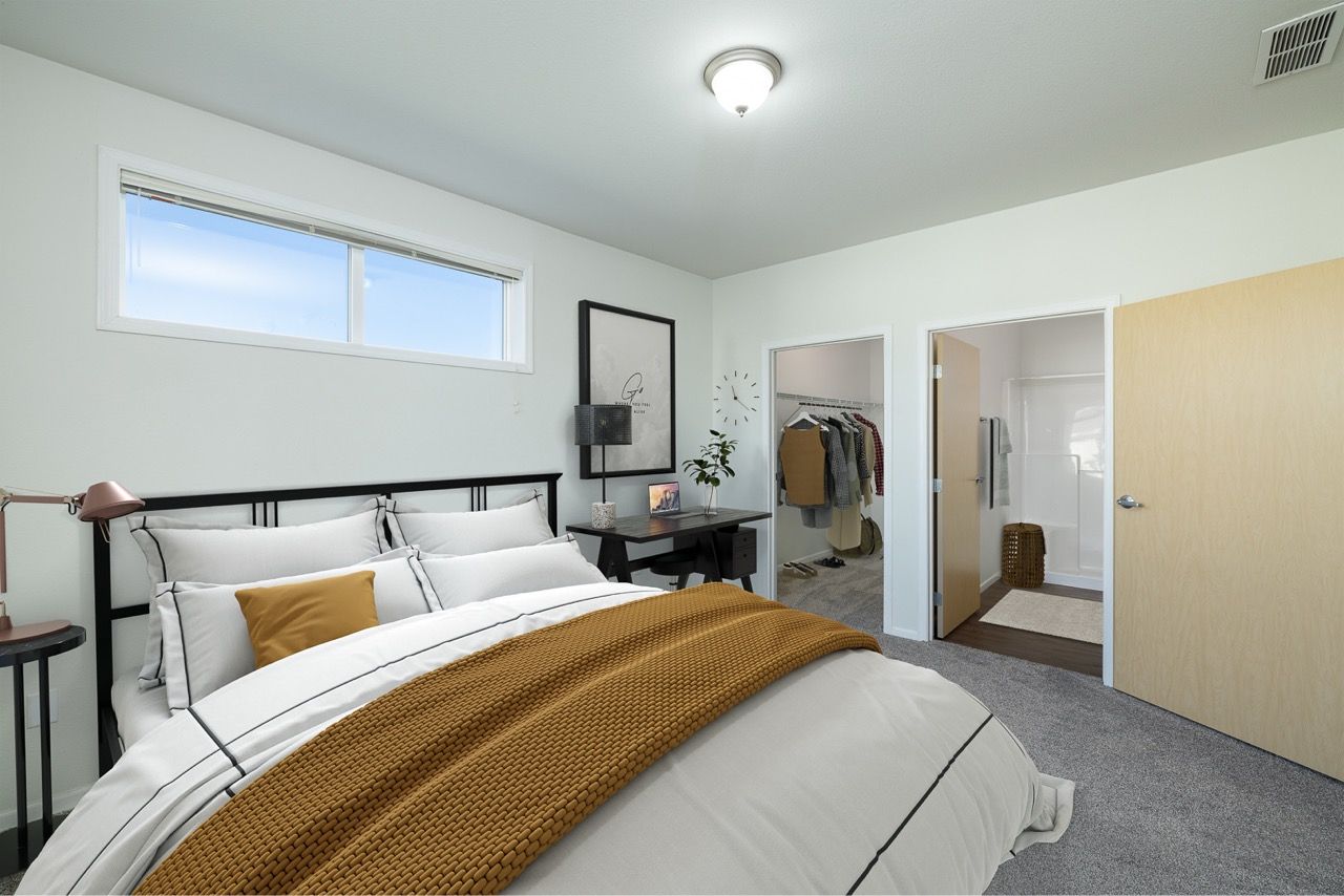 Bedroom with a bed, desk, and open closet; neutral decor and a window.
