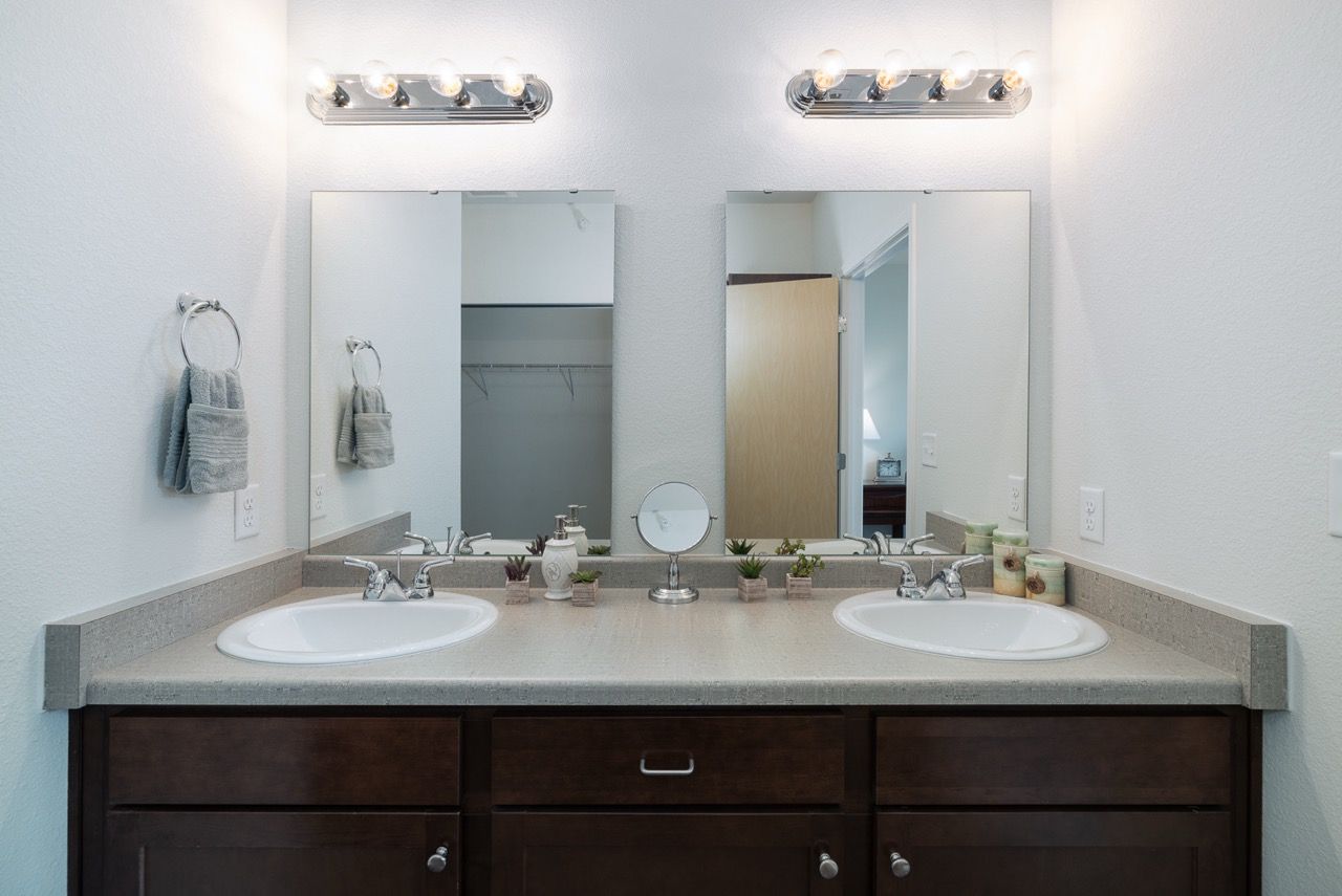 Dual-sink bathroom vanity with mirrors, lights, and towel rings.