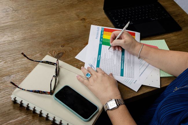 A woman is sitting at a table writing on a piece of paper.