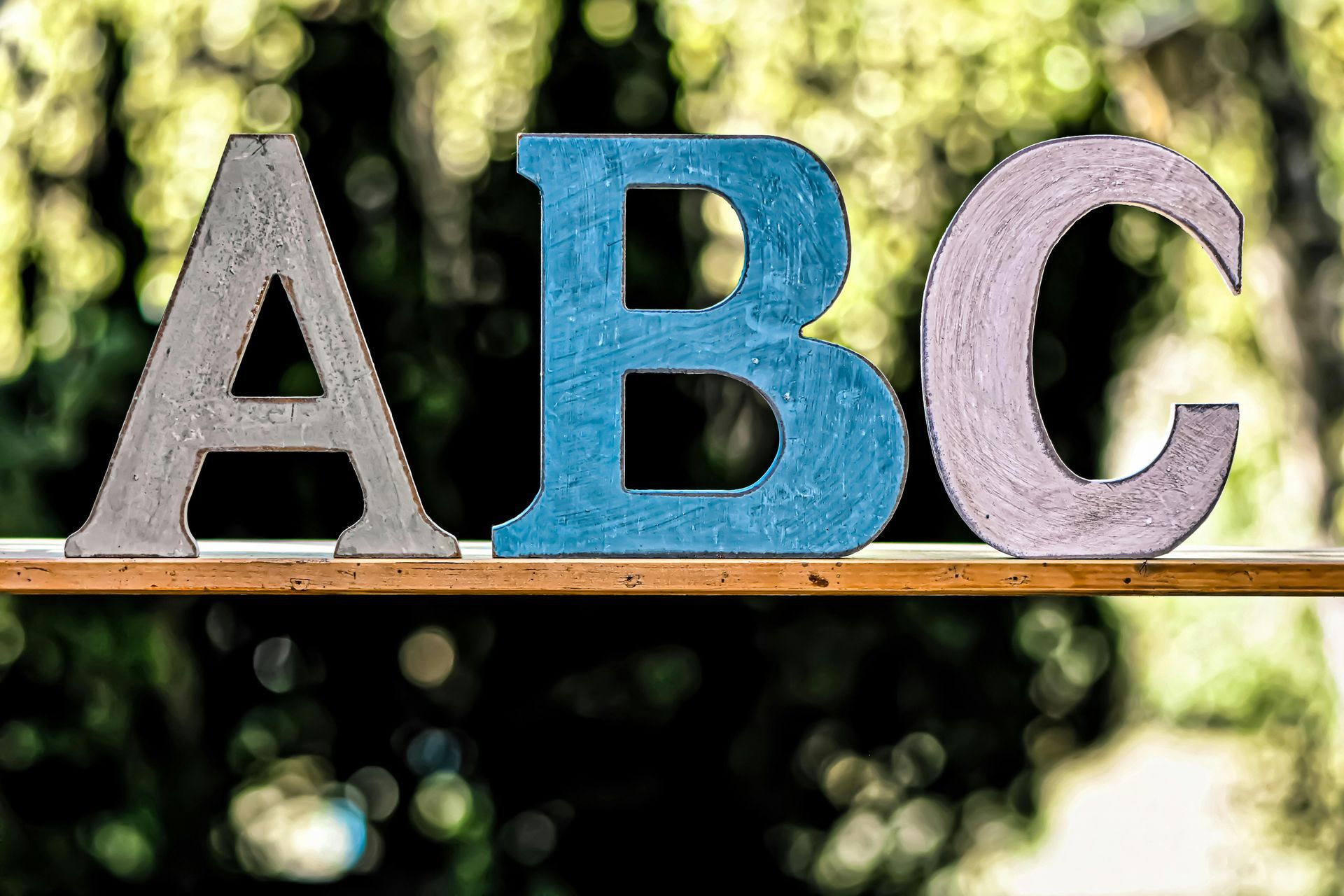 The letters a , b , and c are sitting on a wooden table.