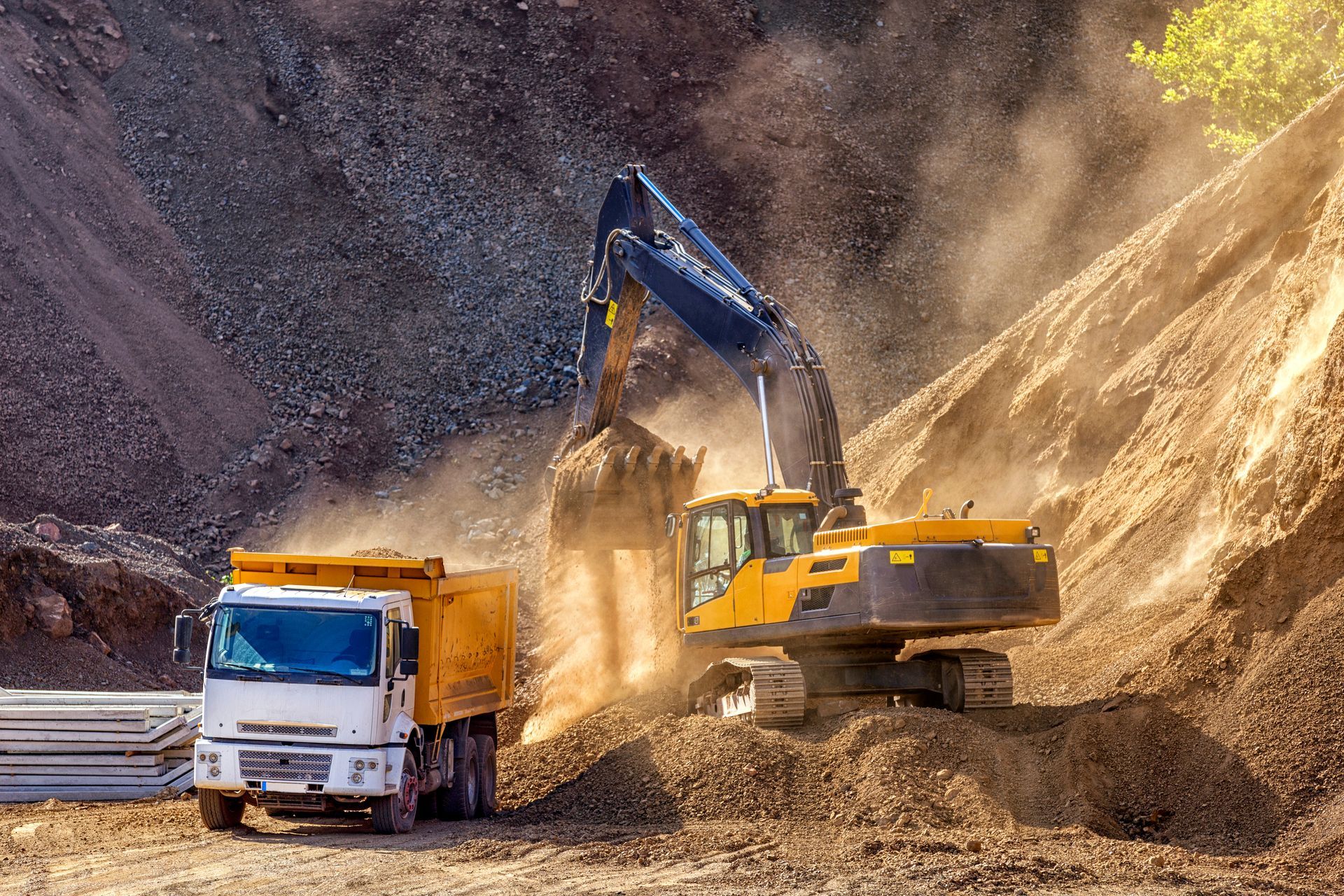 An excavator is loading dirt into a dump truck at a construction site.