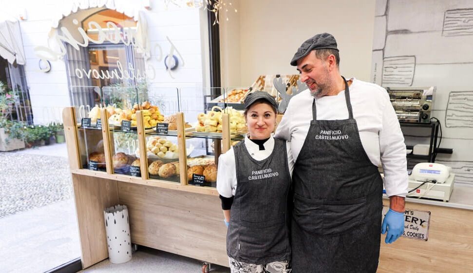 Primo piano di un'esposizione di panini, alcuni con prosciutto, nella vetrina di una panetteria.