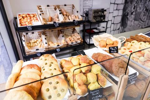 Muffin ripieno di mirtilli tagliato, che rivela un ripieno di frutti di bosco scuri, una copertura friabile e leggera e una fodera di carta marrone.