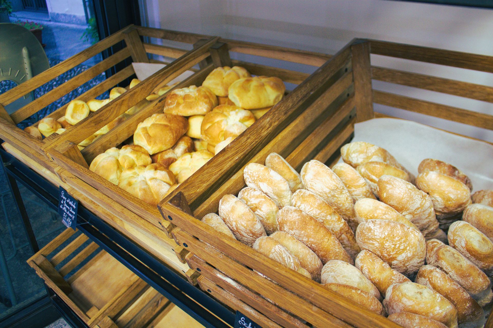 Casse di legno piene di vari tipi di pane: panini e pagnotte, esposizione di prodotti da forno.