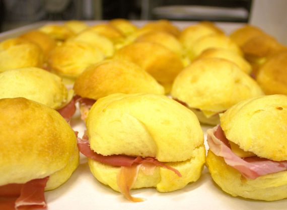 Mini panini su un vassoio: soffici panini gialli con ripieno di prosciutto rosa.