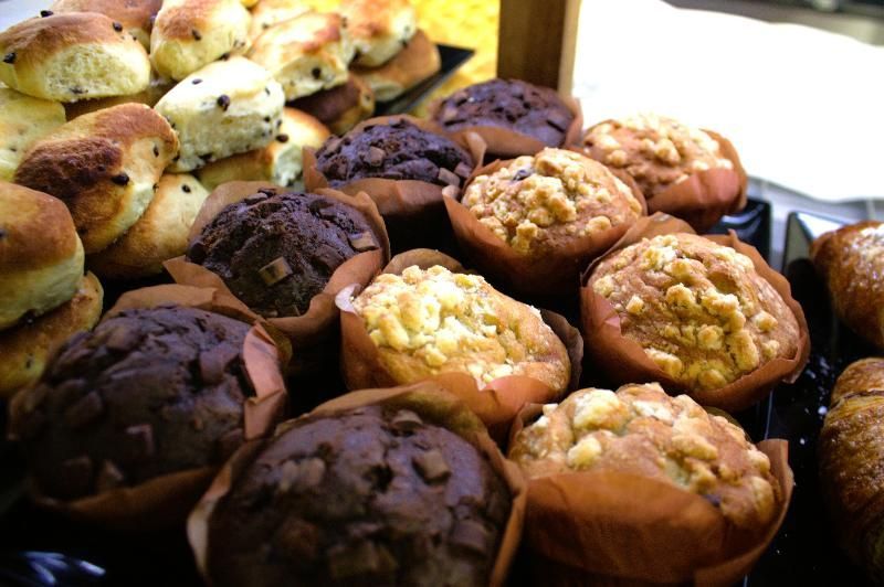 Assortimento di muffin e scones in pirottini di carta, alcuni con gocce di cioccolato.