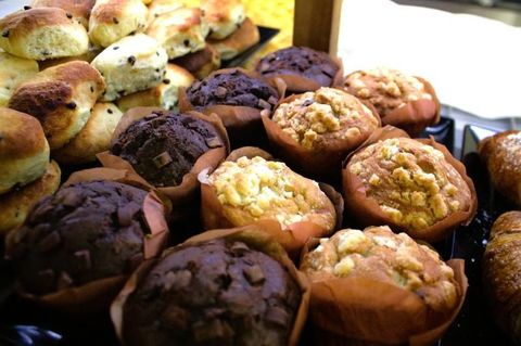 Assortimento di muffin e scones in pirottini di carta, alcuni con gocce di cioccolato.