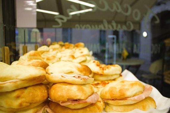 Primo piano di un'esposizione di panini, alcuni con prosciutto, nella vetrina di una panetteria.