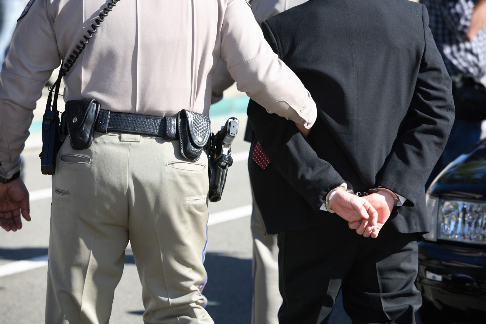 A man in a suit is being escorted by a police officer