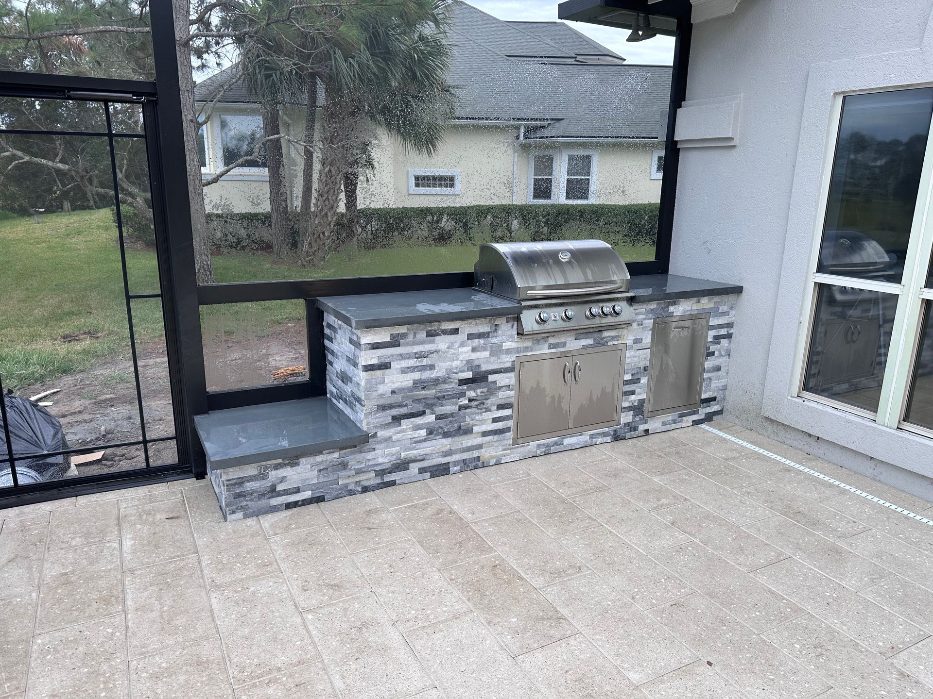 Outdoor kitchen with grill, cabinets, and counter on a patio.