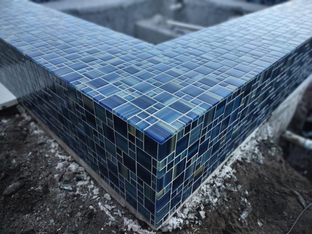 Blue mosaic tile edging around a pool under construction.