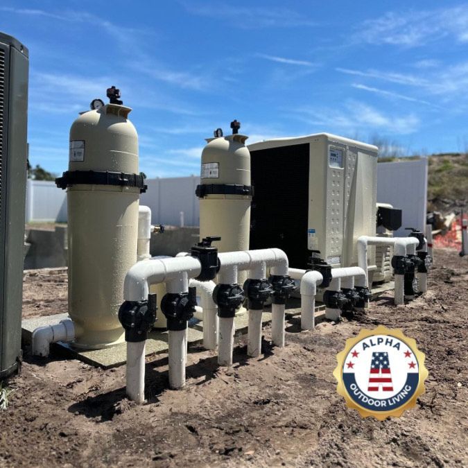 Pool equipment setup outdoors with filters, pipes, and a control unit, on a dirt ground under a blue sky.