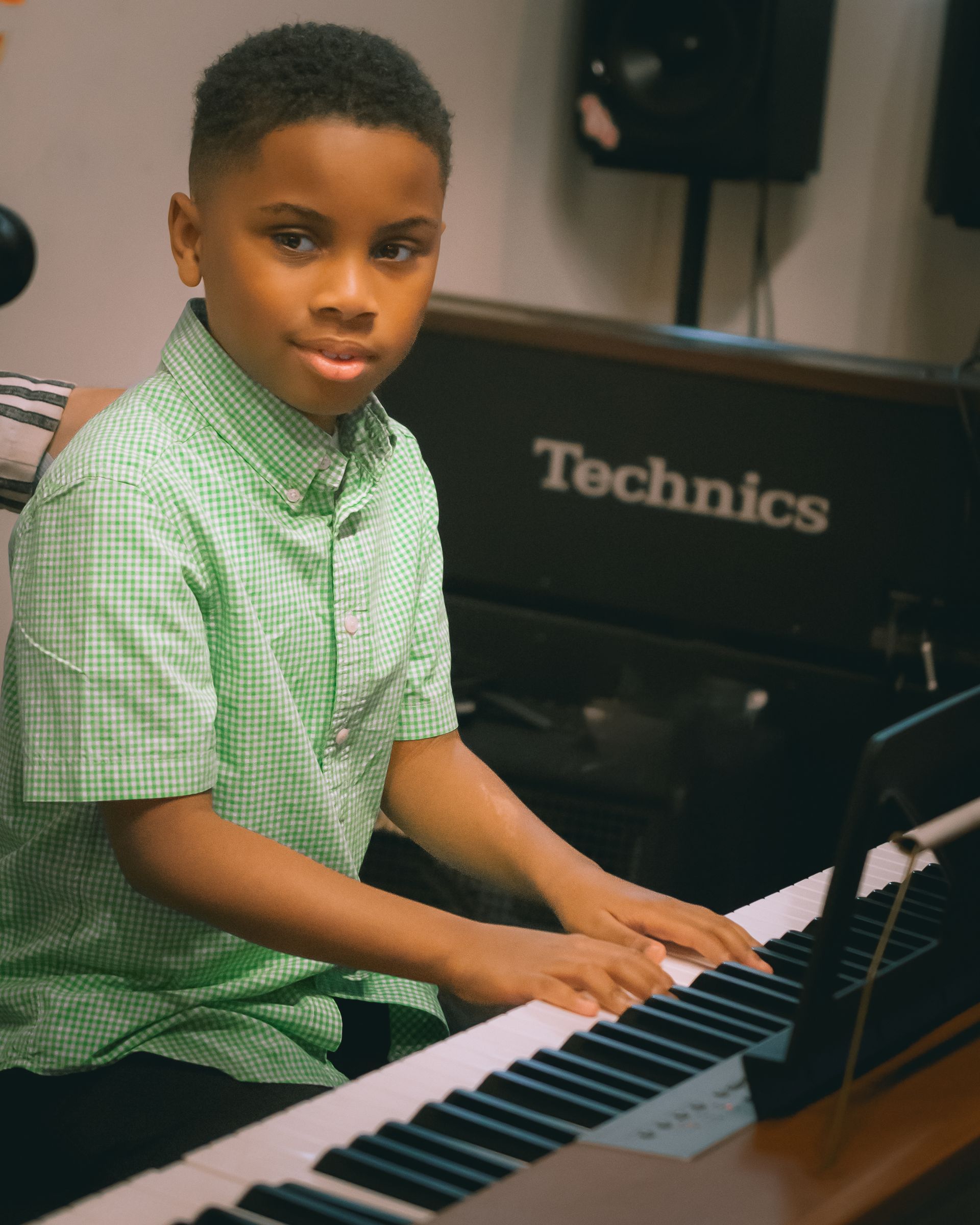 A young boy is playing a technics keyboard