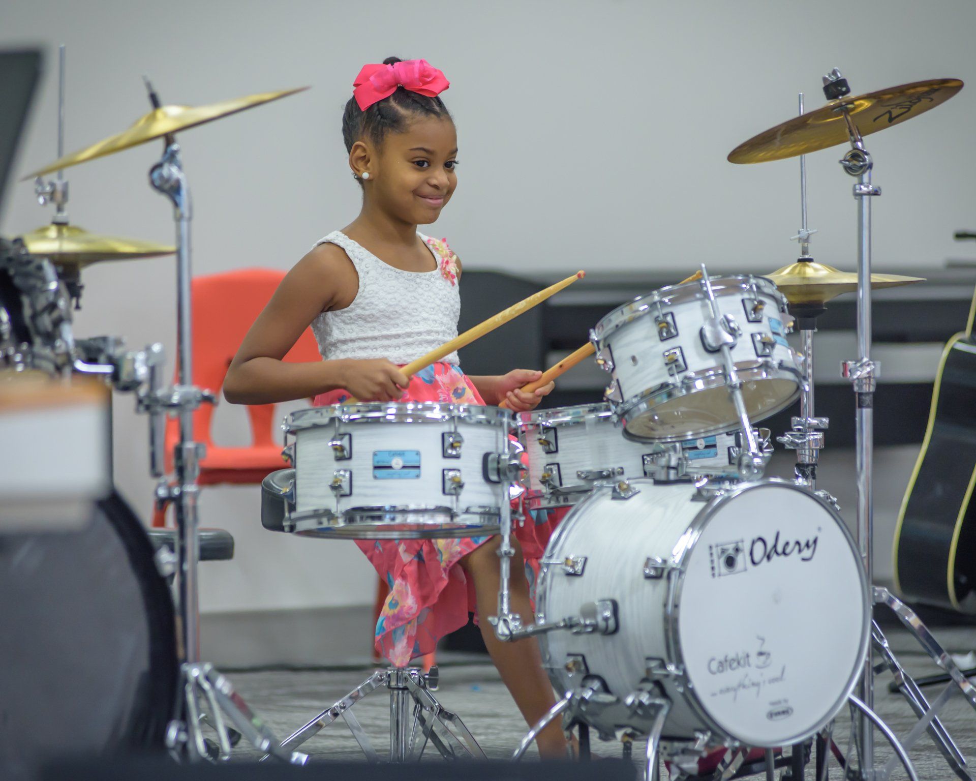 A young girl is playing drums in a room.