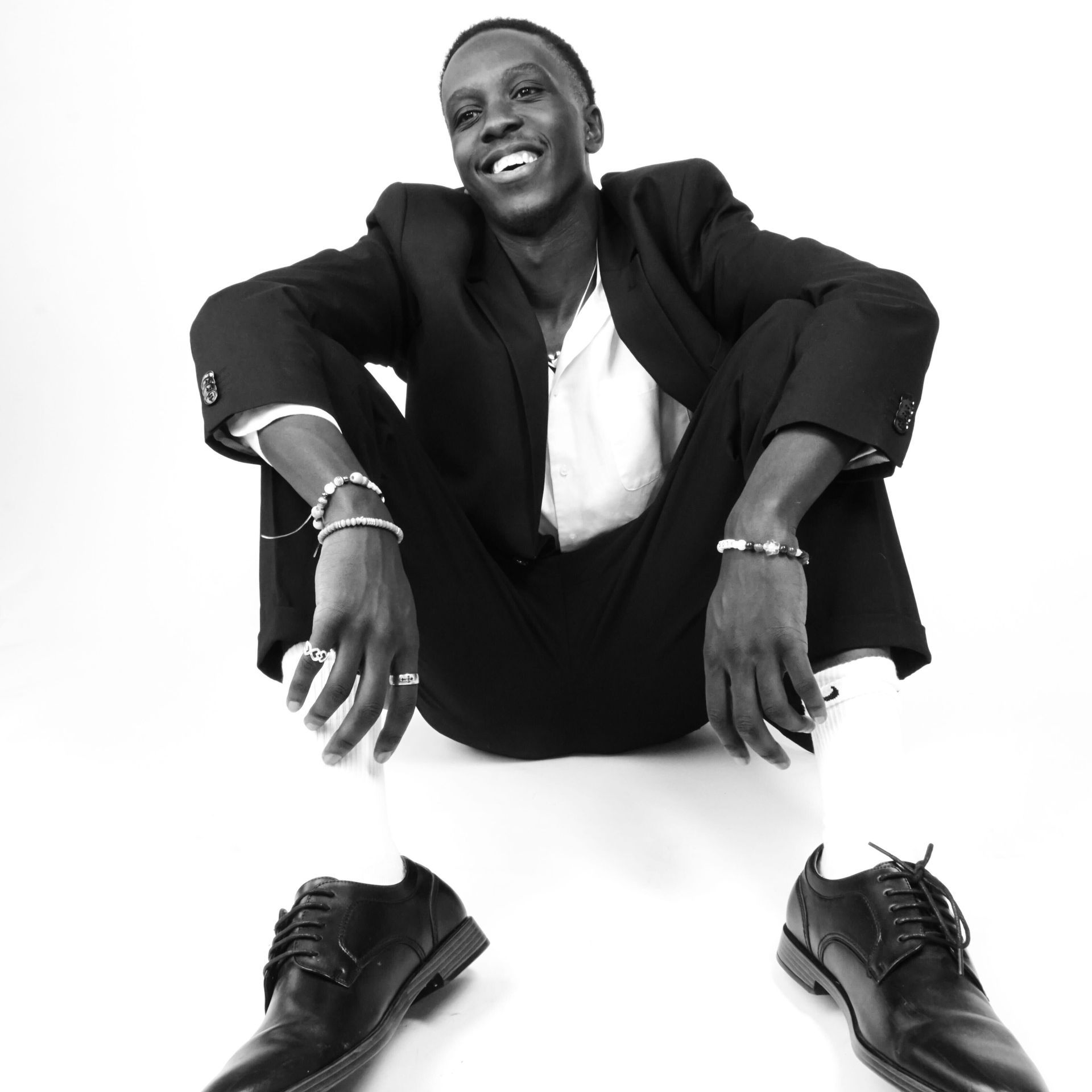 A young man standing in front of a wall with paintings on it
