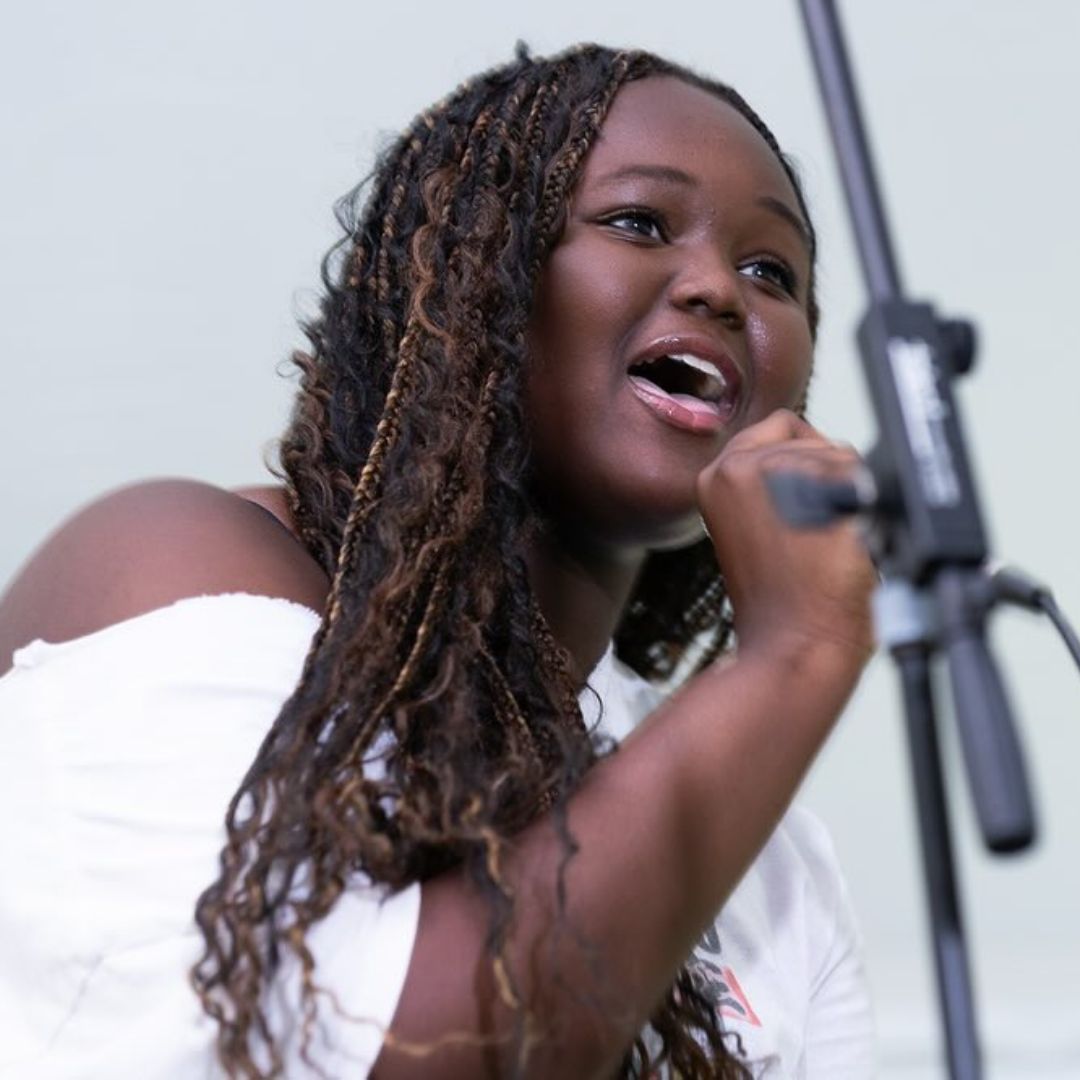 A woman singing into a microphone that says ' yamaha ' on it