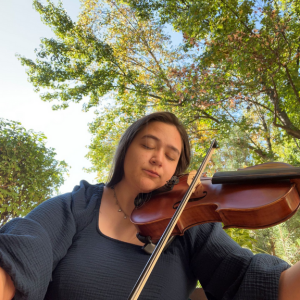 A woman is playing a violin with her eyes closed