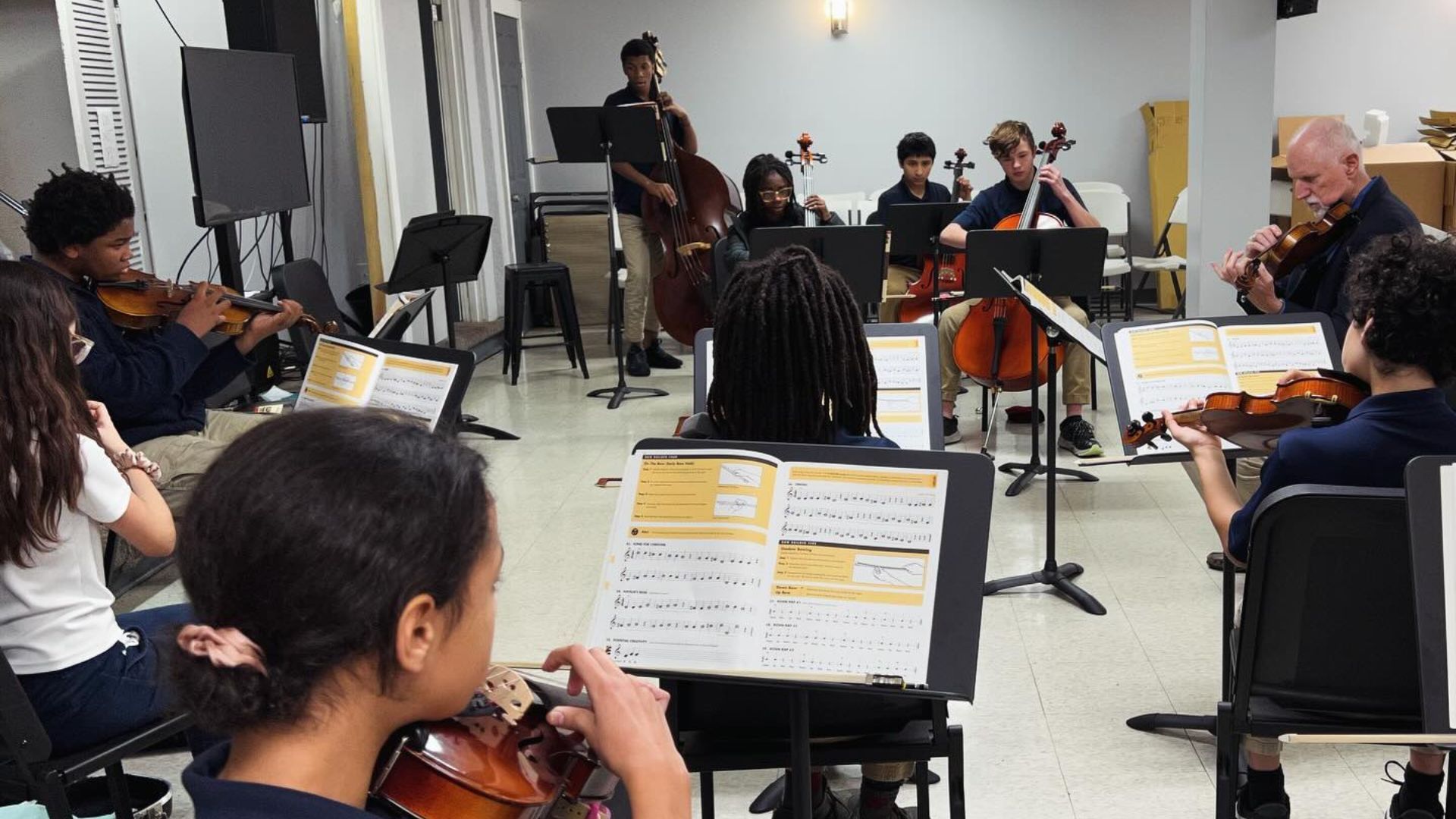 A group of people are playing violins and cello in a room.