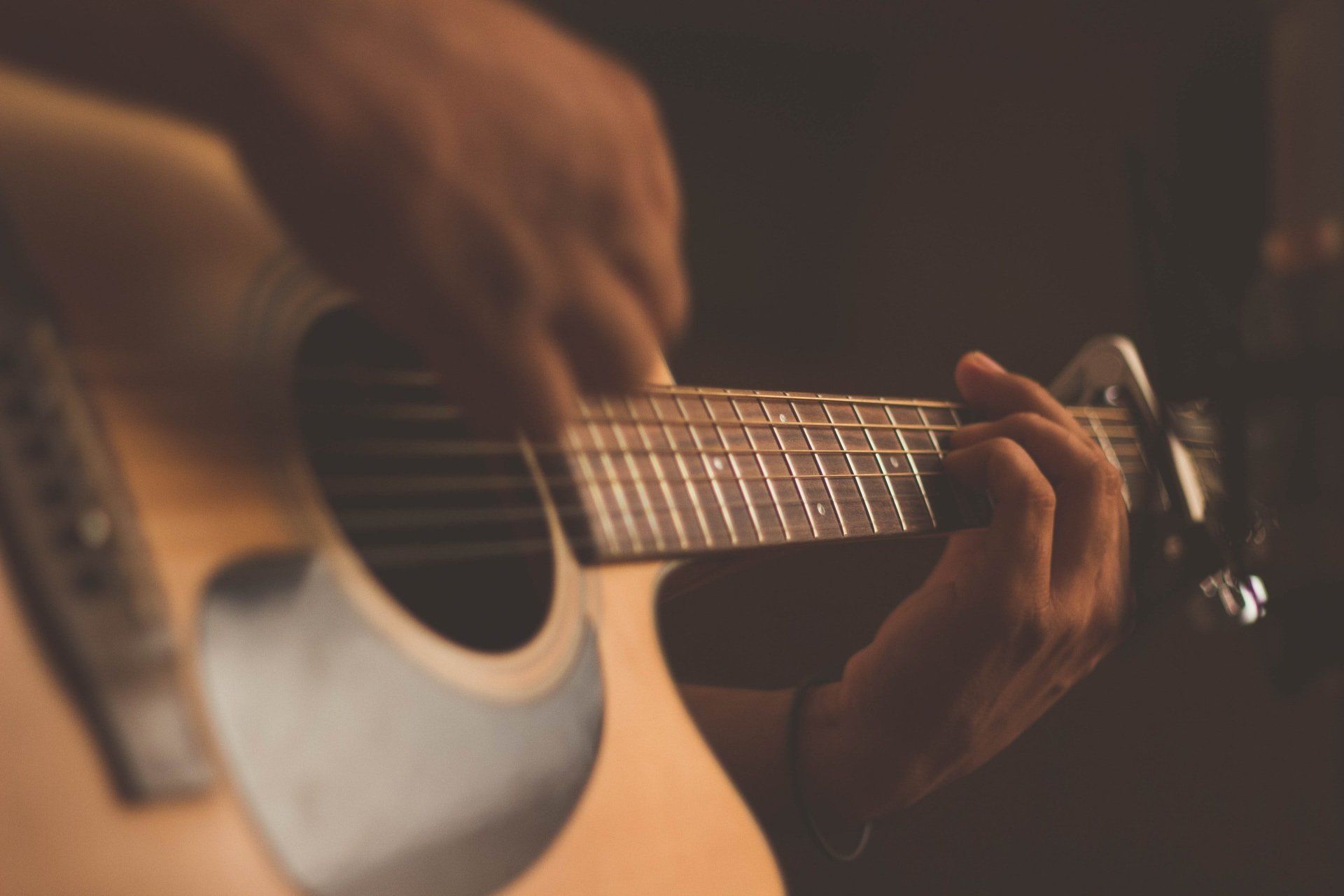 A person is playing an acoustic guitar in a dark room.