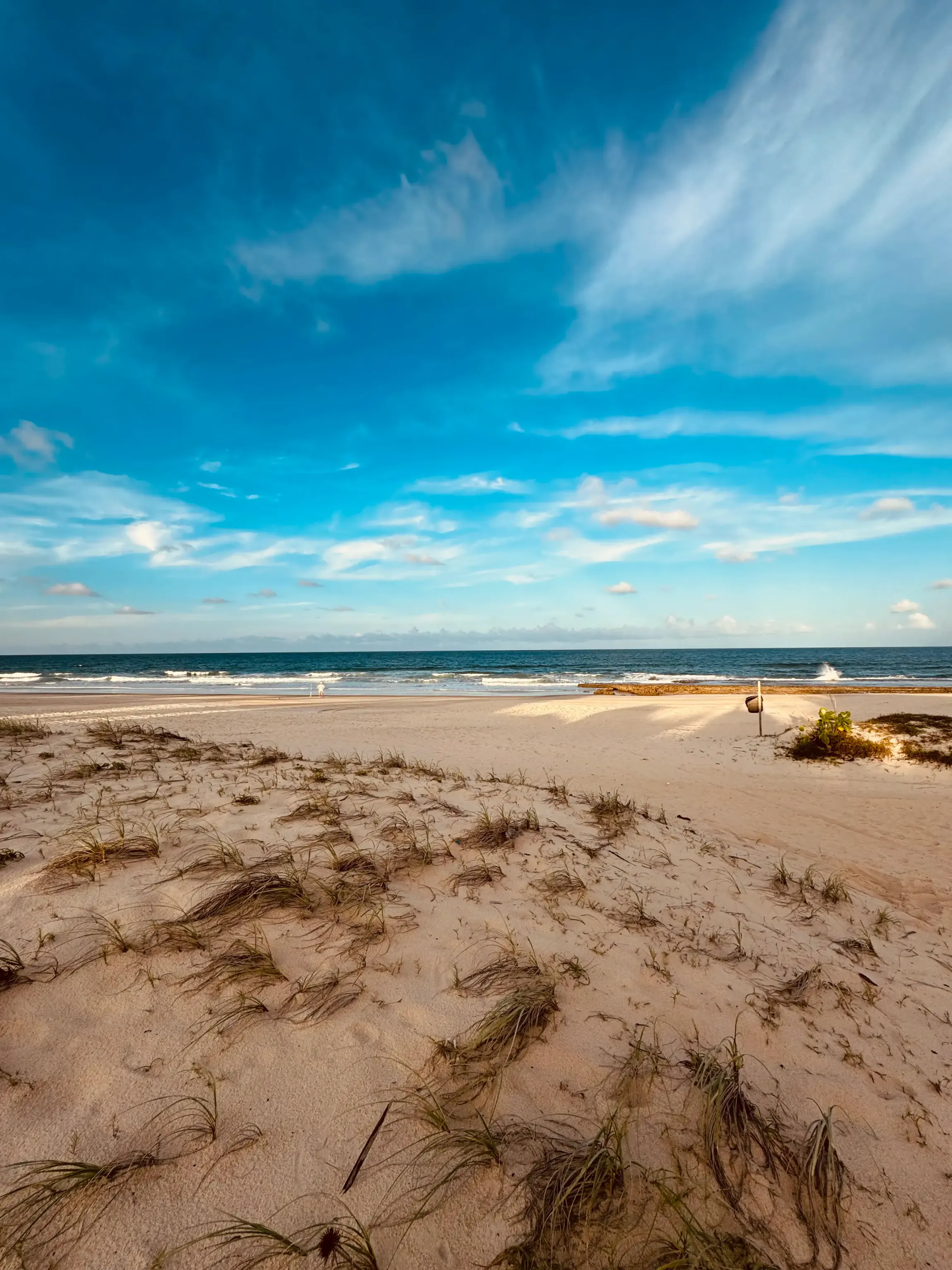 Uma praia de areia com um céu azul e o oceano ao fundo. - Villa Manzuá