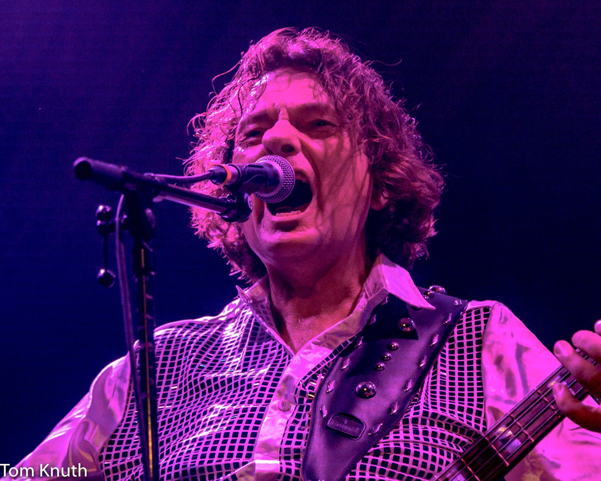 A man singing into a microphone while holding a guitar