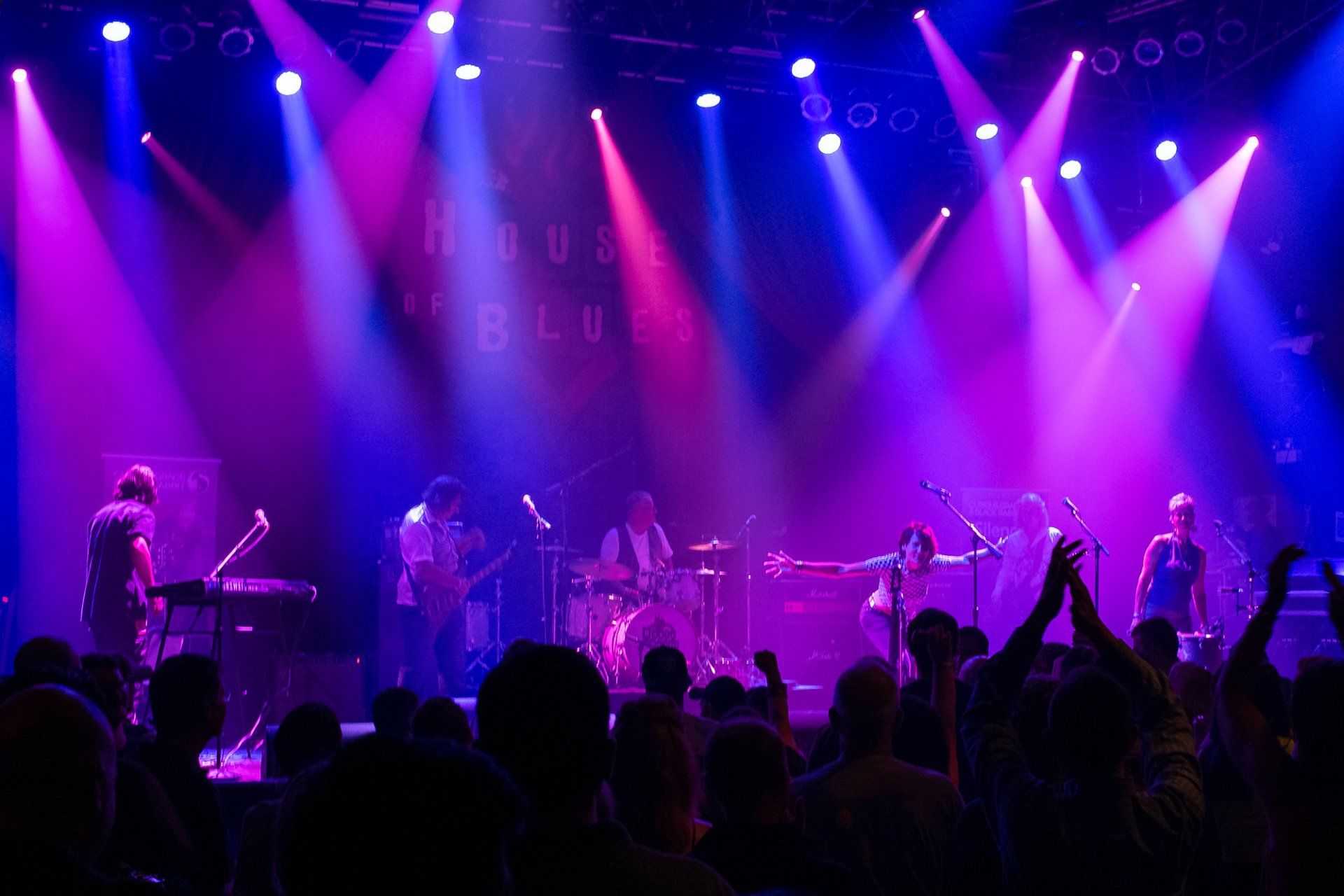 A group of people are standing in front of a stage with purple lights