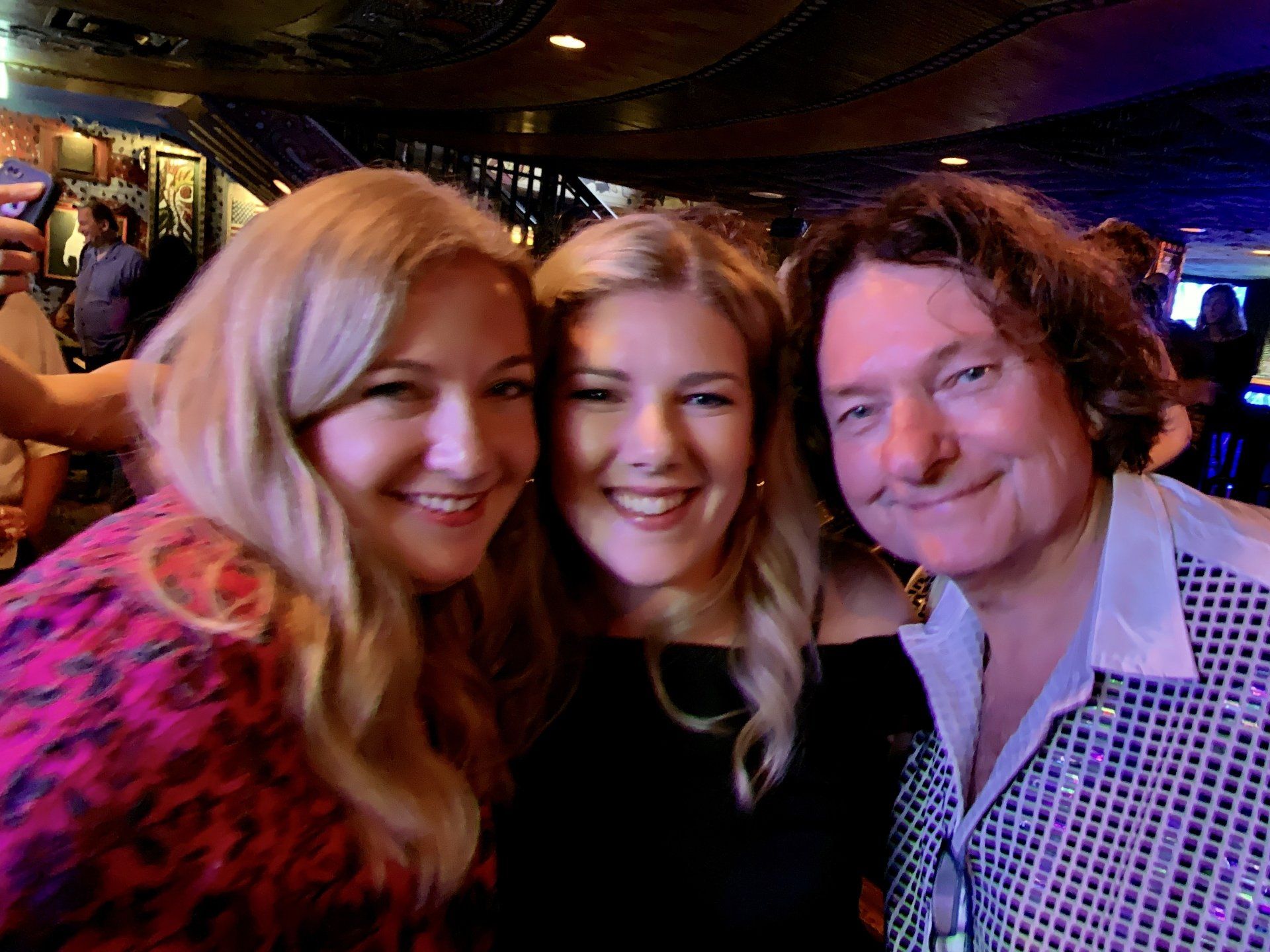 A man and two women are posing for a picture in a bar.