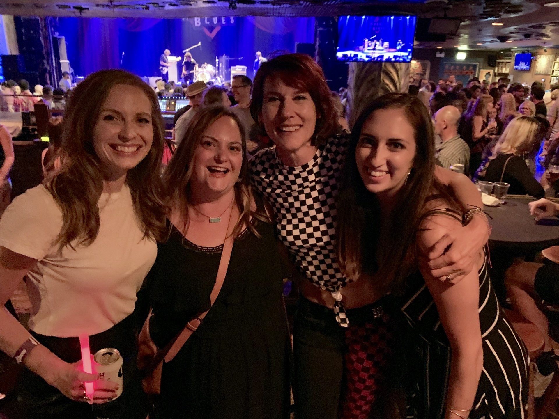 A group of women are posing for a picture at a concert.