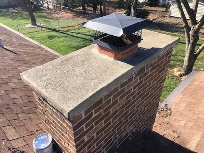 A brick chimney with a metal cap on top of it.