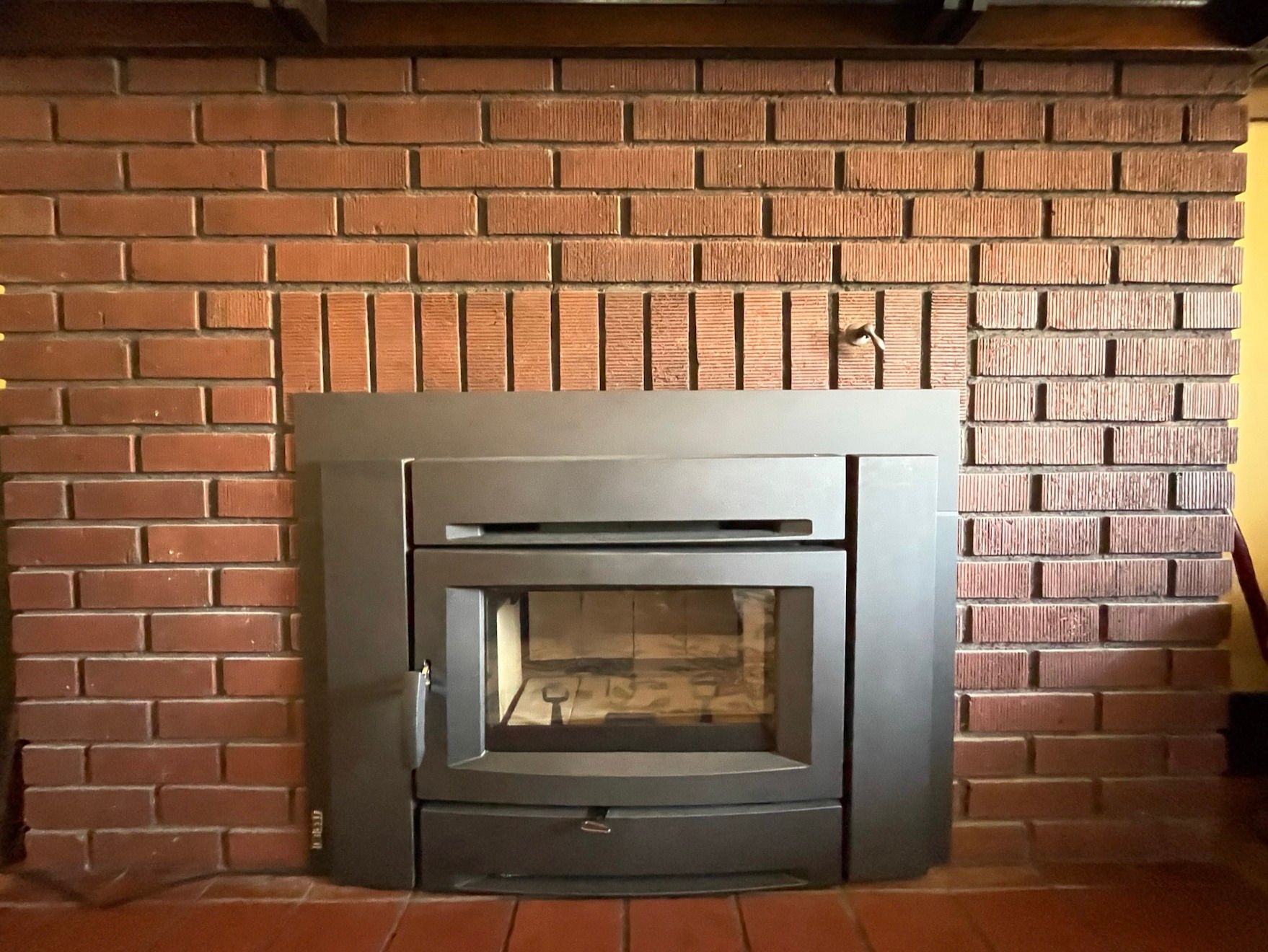 A brick fireplace with a black stove in it