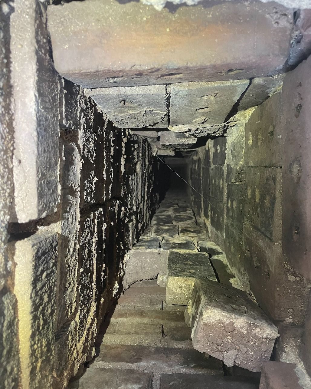 A brick tunnel with stairs going down it