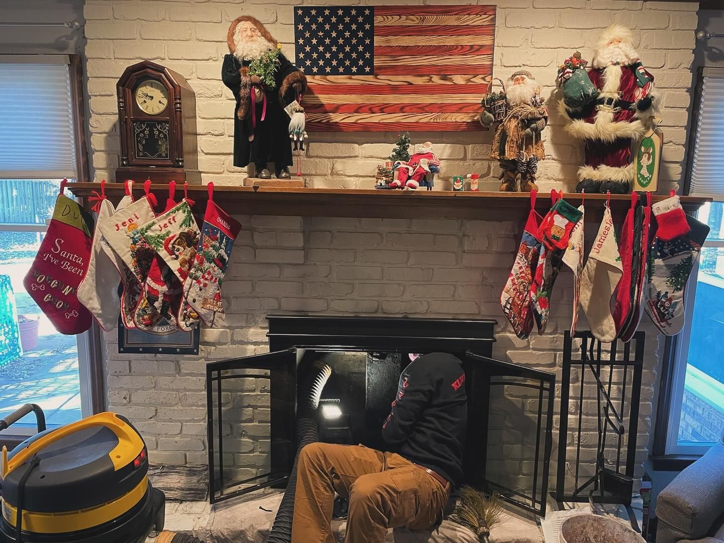 A man is sitting in front of a fireplace decorated for christmas.