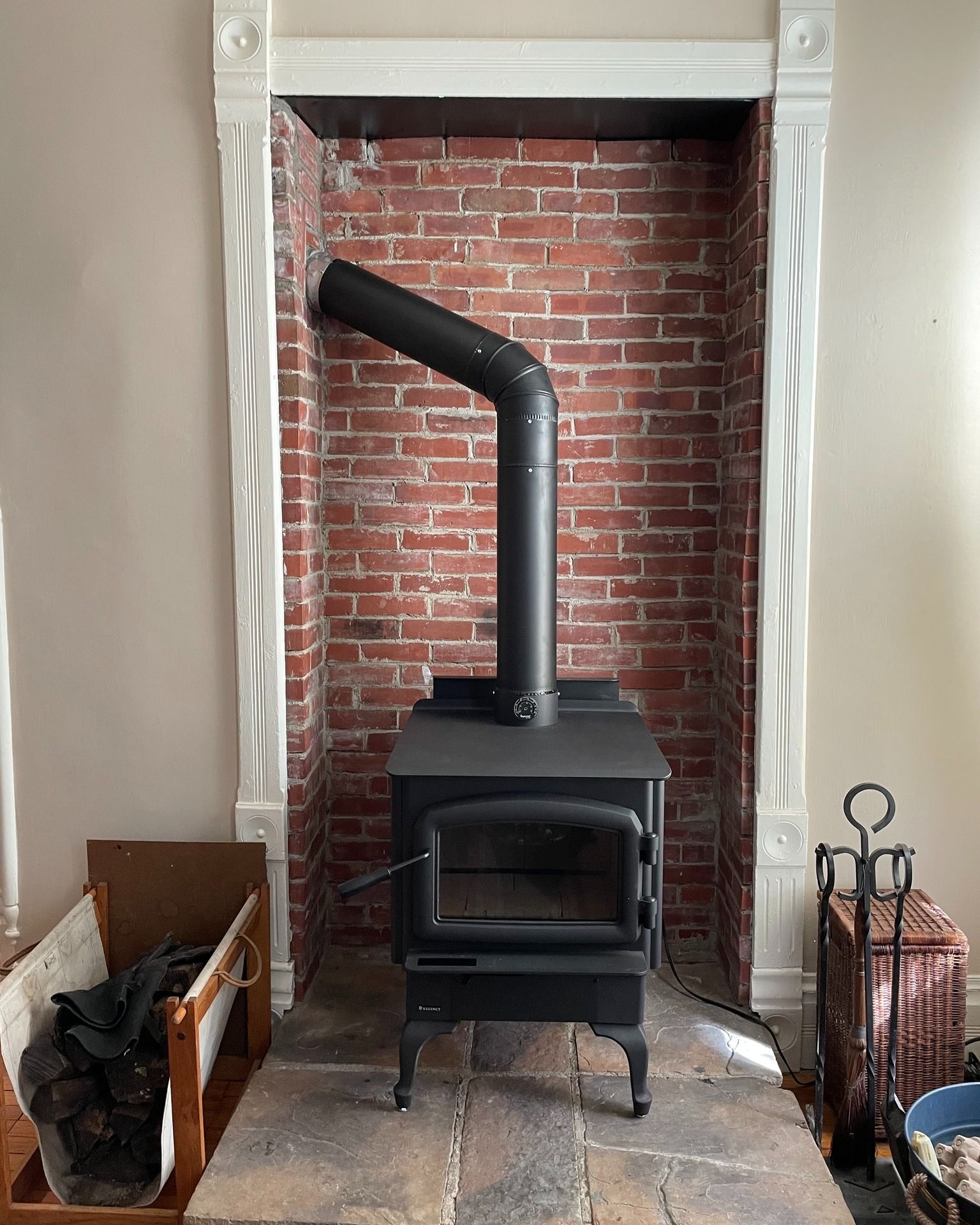 A wood stove is sitting in a brick fireplace.