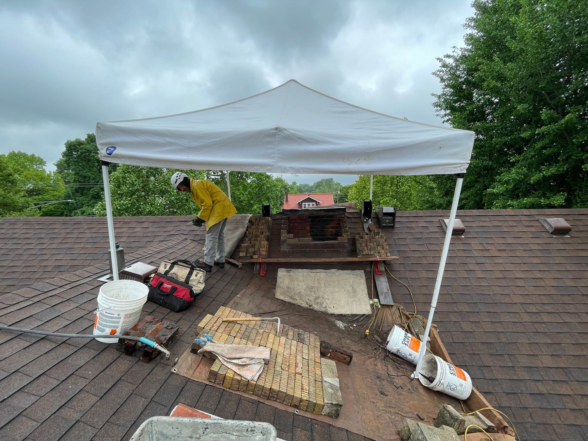 A man is working on a roof under a tent.