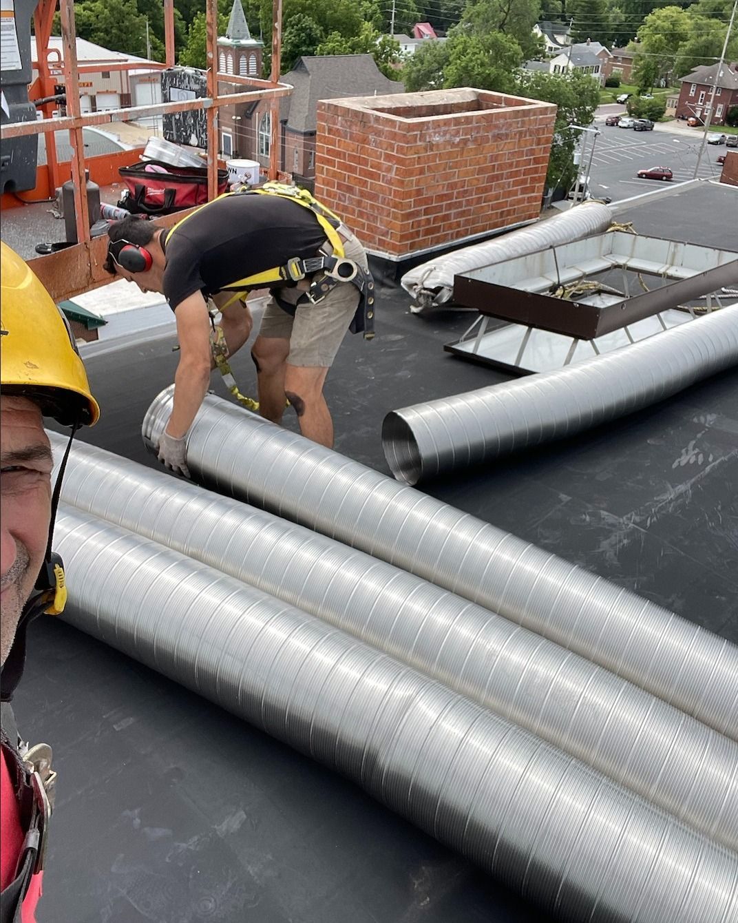 A man wearing a hard hat is working on a roof
