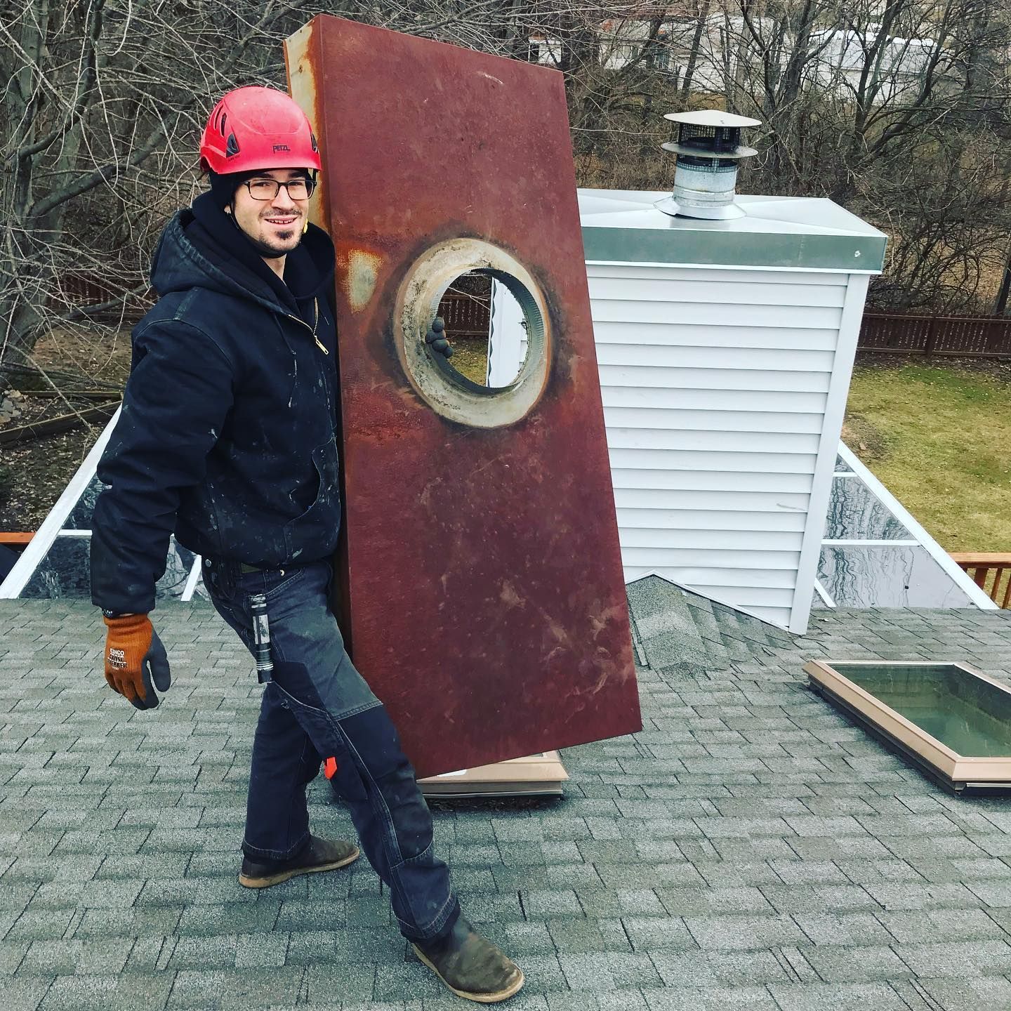 A man is carrying a large piece of metal on a roof.