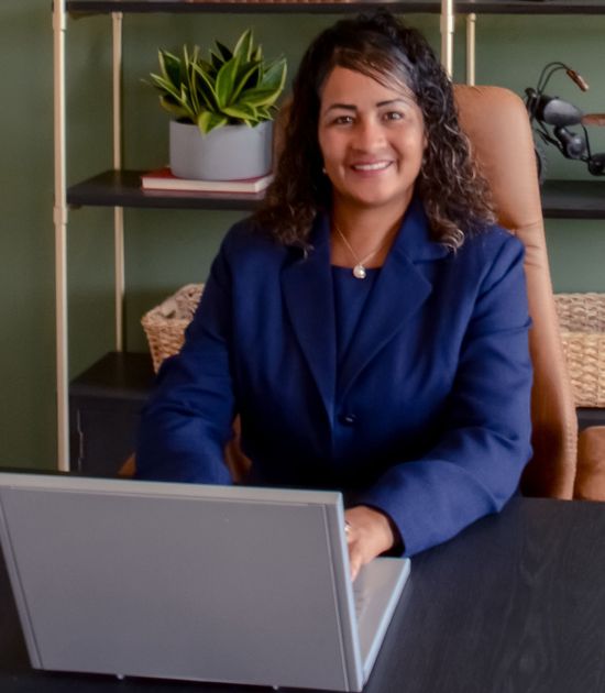 A woman is sitting at a desk with a laptop.
